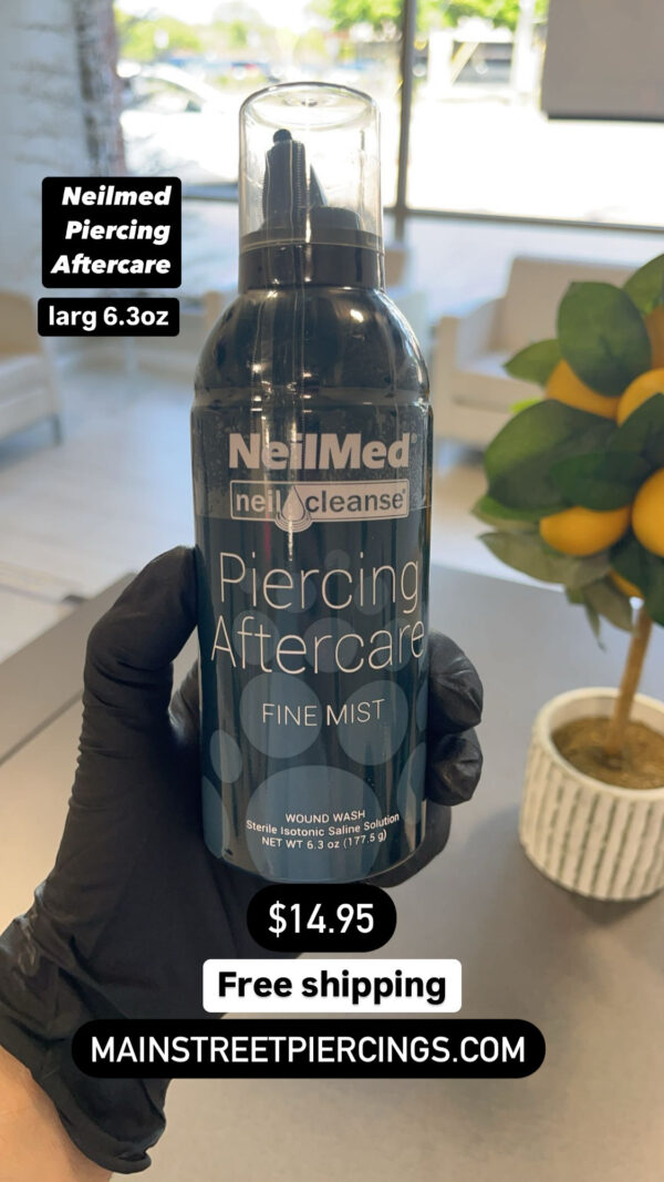 A person holding up a bottle of piercing aftercare.