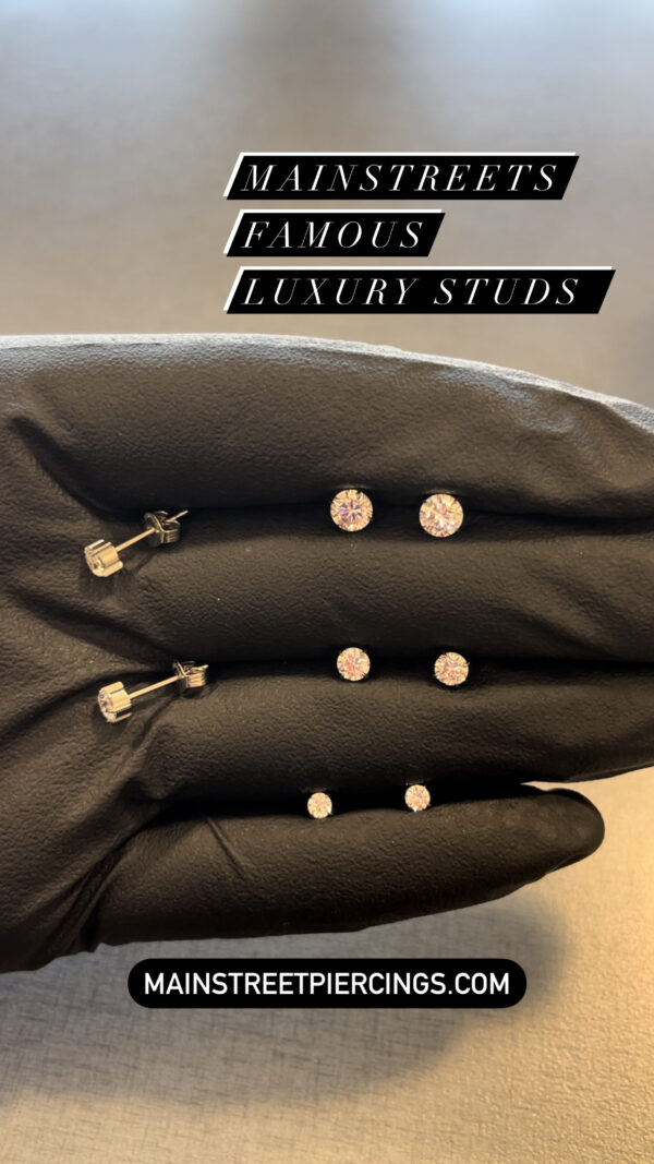 A pair of black gloves with four pairs of earrings.