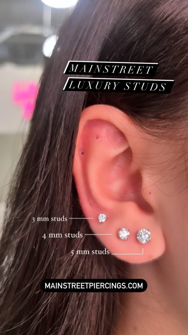 A woman 's ear with four pairs of earrings.