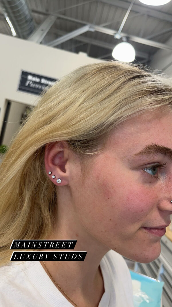 A woman with long blonde hair wearing ear piercings.