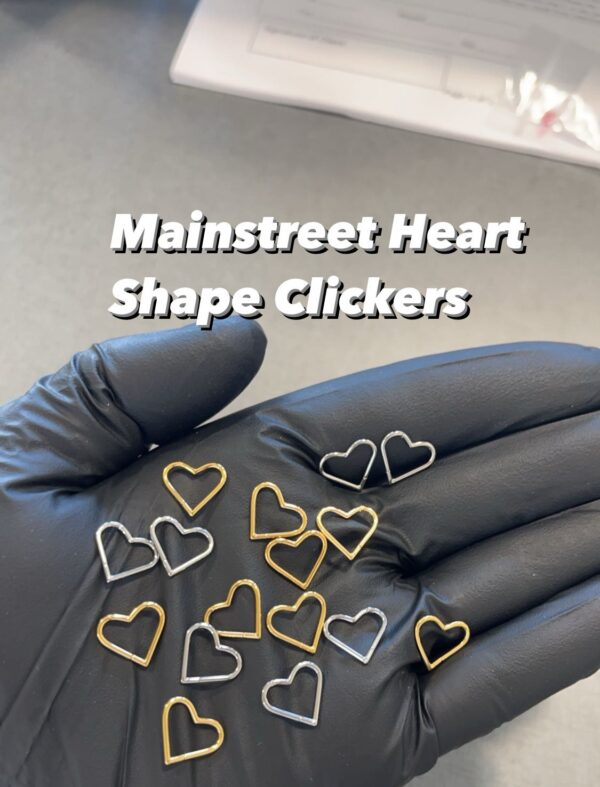 A hand with many heart shaped metal clips on it.